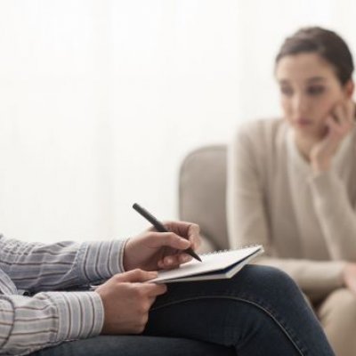 Woman sitting near another person writing notes.